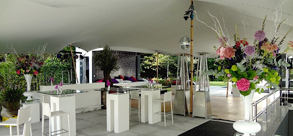 Hochzeitszelt von Intertent Zeltvermietung - Innenansicht Stretchzelt mit weißer Zelt-Ausstattung, Terrasse, Eventstyling und Blumen