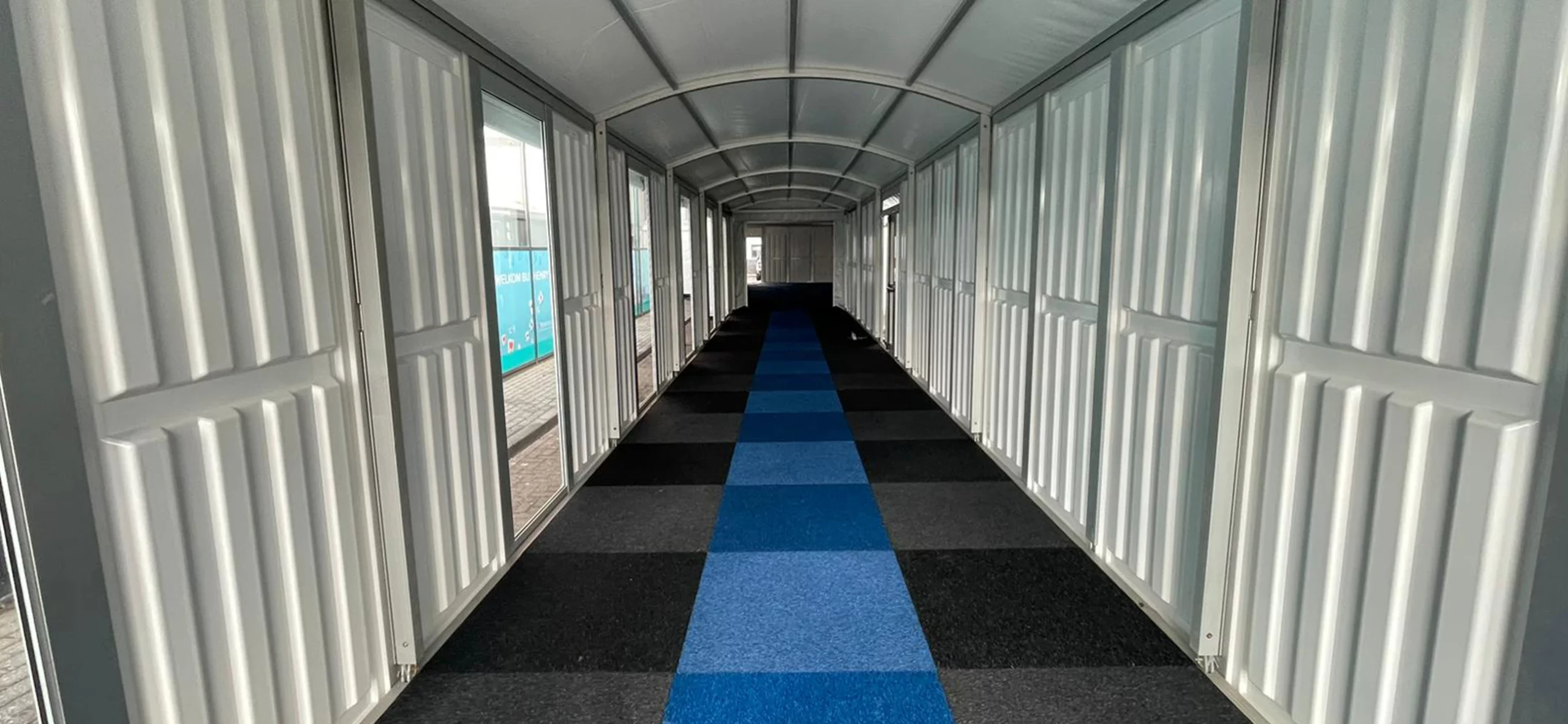 Pergola Walkway mit Hartschalenwandpaneelen und Teppichboden - Innenansicht eines Übergangs zur Eventlocation