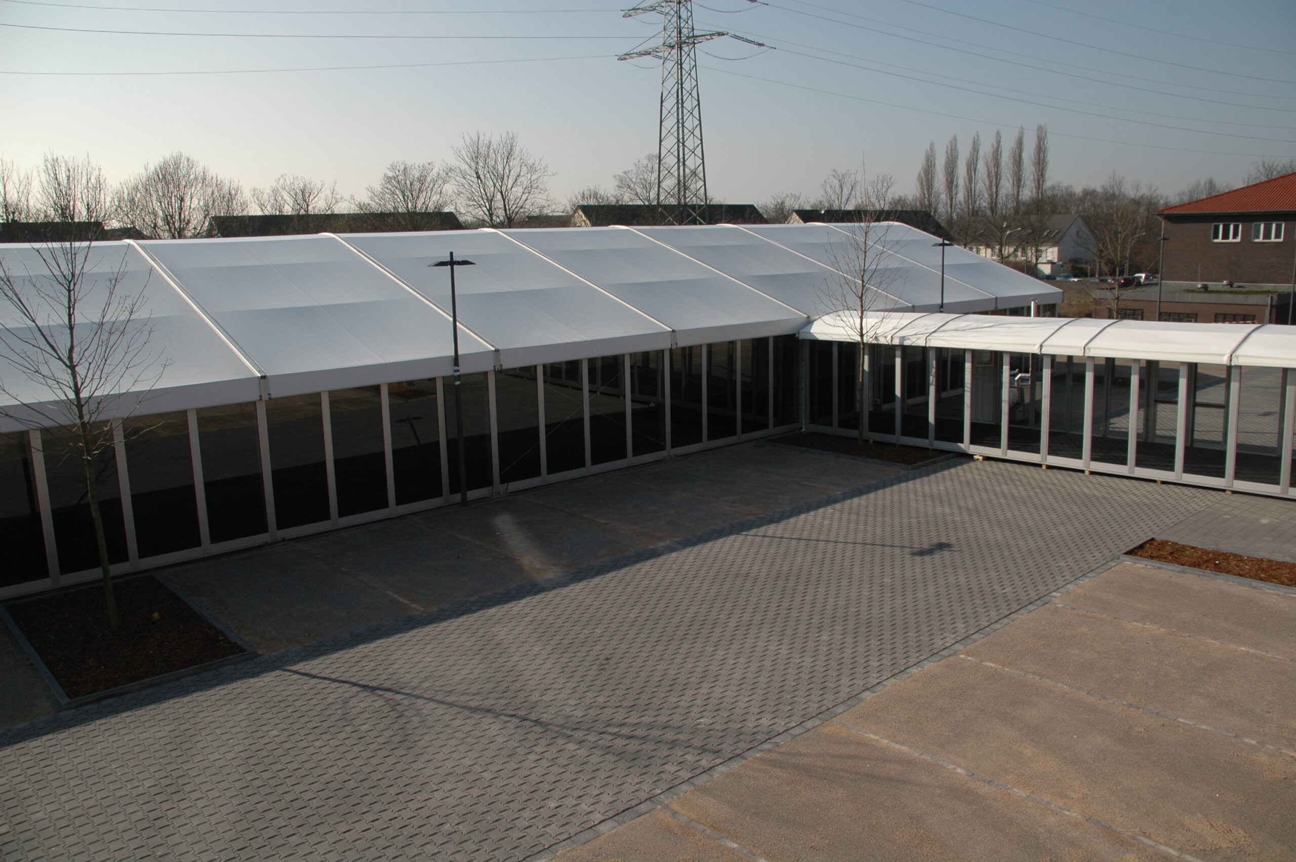 Zeltverleih Intersettle - Pergola Walkway zur Verbindung von Veranstaltungszelten mit Gebäuden und als Empfang - eleganter, schützender Übergang mit Seitenwänden aus Glas mit Panoramaausblick