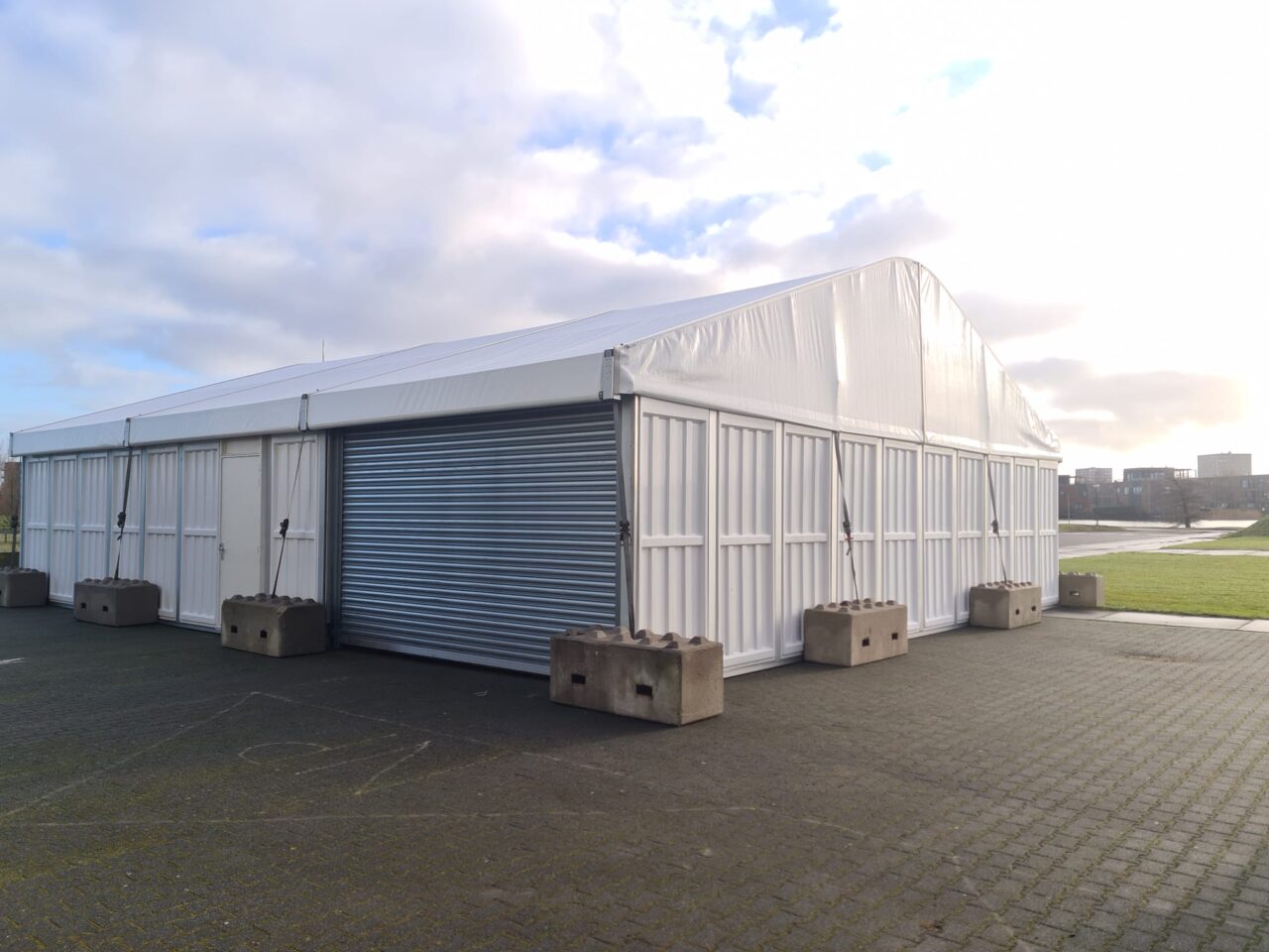 Lagerhalle mit Rolltor und separatem, gesichertem Eingang und Betonverankerungen von Zeltverleih Intersettle - Funktionale, robuste und standsichere Hallen