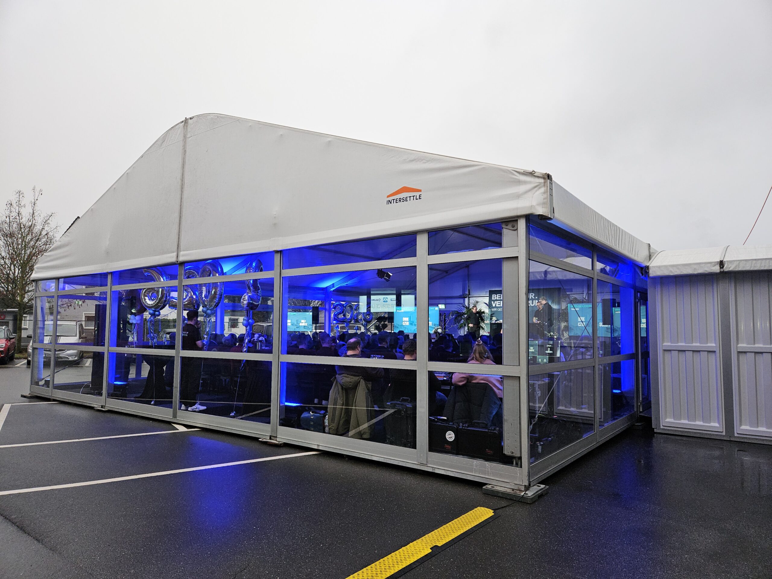 Raumlösung für Tagungen - Zelthalle Alu Vision (12x15m) mit horizontalen Glasfassaden von Intersettle Zeltverleih und Pergola Walkway für direkten Übergang ans Firmengebäude - PPG Jahresauftaktevent 2026