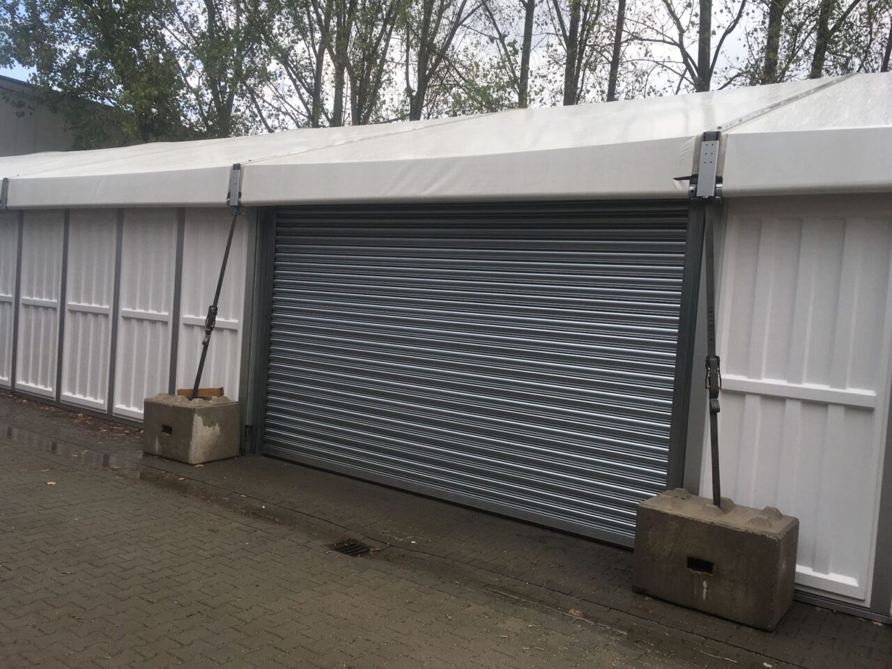 Seitenansicht Lageerzelt mit Rolltor und Betonverankerungen von Intersettle Zeltverleih für Industrie und Gewerbe