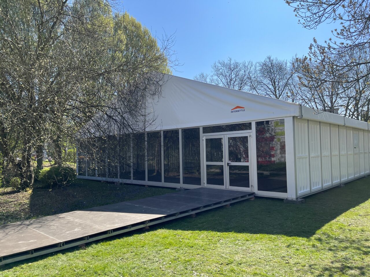 Frontansicht Zelthalle Alu Pavillon mit Glasfassade und Bodenschutz von Intersettle Zeltverleih - temporäre Raumlösung für Gesamtschule in Essen als Ausweichort für Veranstaltungen