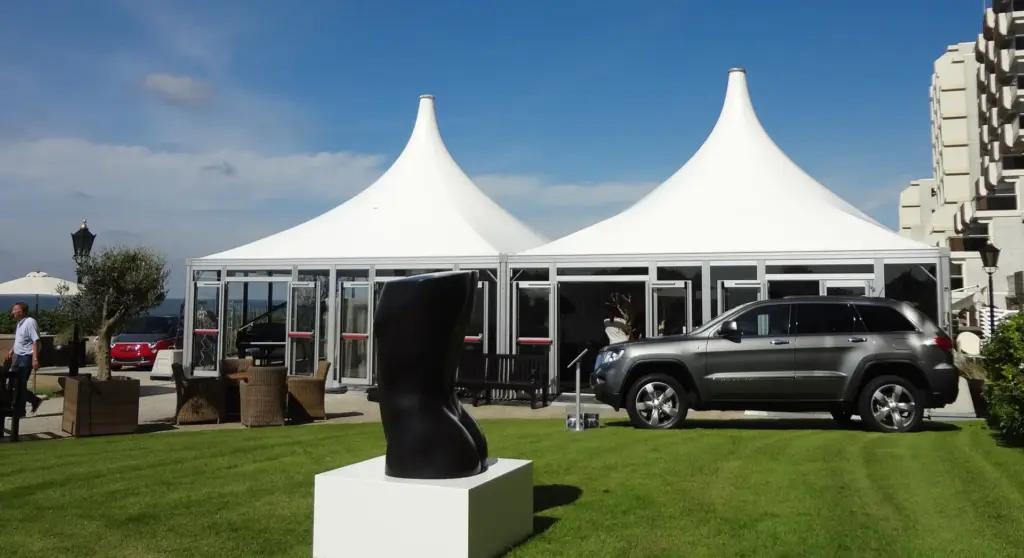 Zwei Carré Pagoden mit Spitzdach und Glaspaneelen als Pavillons zur Präsentation von Autos