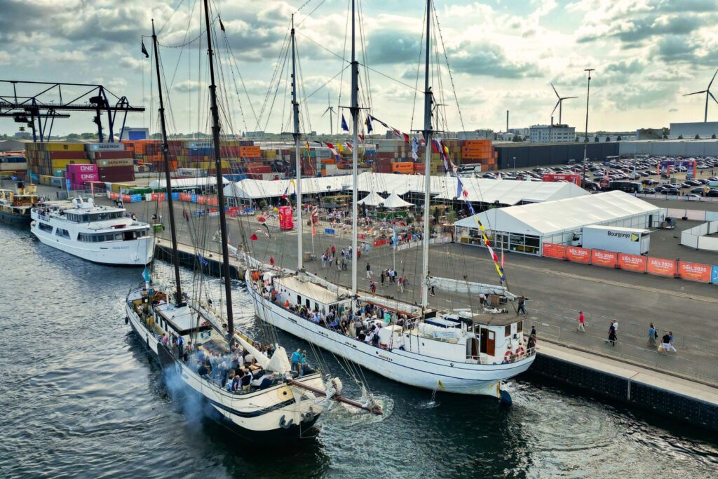 Drei Segelschiffe am Kai der SAIL Villages mit Zelten, Pagoden und Zelthallen von Intersettle Zeltverleih auf der SAIL Amsterdam 2025